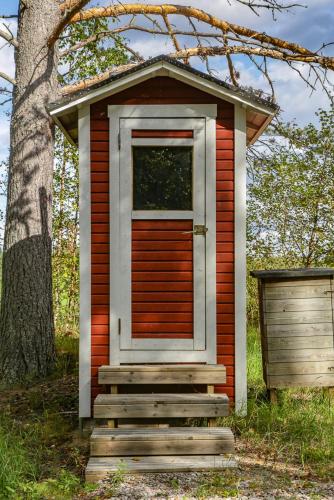 una pequeña casa con una puerta y escaleras delante de un árbol en Lammashaan tupa lammen rannassa, en Ruovesi