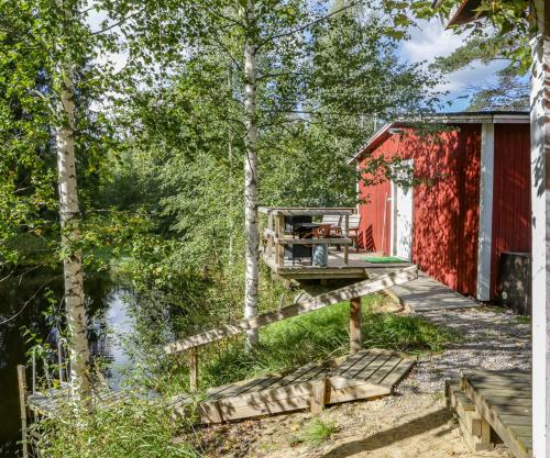 a red cabin with a deck next to a body of water at Lammashaan tupa lammen rannassa in Ruovesi