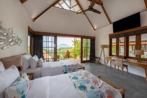 a bedroom with a bed and a desk in a room at Deep Roots Dive & Yoga Resort in Nusa Penida