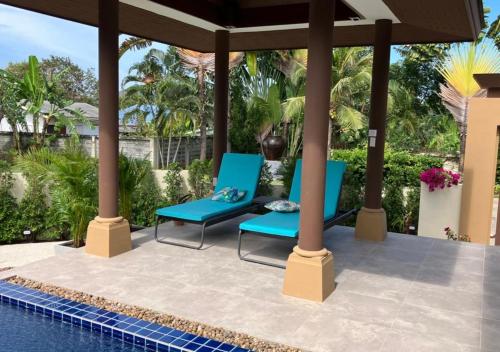 Kluai Mai Luxury Pool Villa, Panorama Resort في هوا هين: فناء مع كراسي زرقاء بجوار حمام سباحة