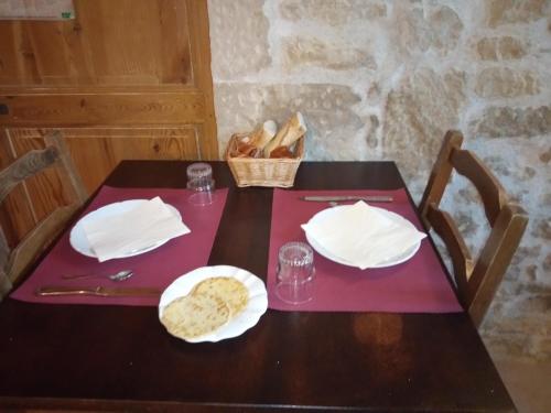 a table with a plate of bread and a basket of bread at Hôtel du Donjon in Aulnay