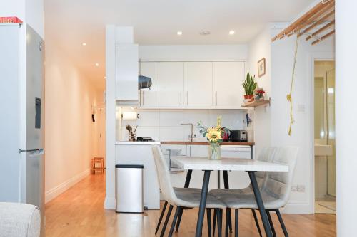 a kitchen and dining room with a table and chairs at Bright 2-bed garden flat with skylights in Chelsea in London