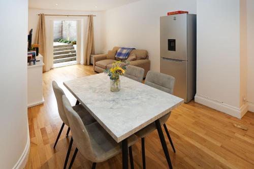 a kitchen and dining room with a table and chairs at Bright 2-bed garden flat with skylights in Chelsea in London