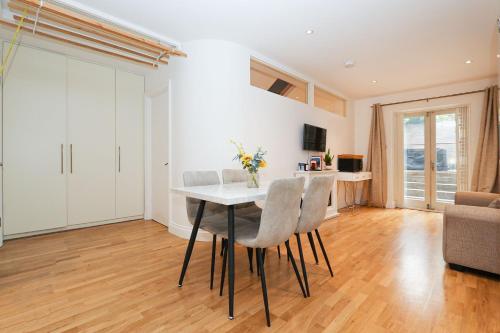 a kitchen and living room with a table and chairs at Bright 2-bed garden flat with skylights in Chelsea in London