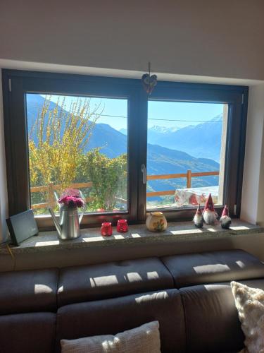 a living room with a couch and a large window at Maison fleurie in Gignod