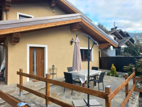 a patio with a table with chairs and an umbrella at Maison fleurie in Gignod