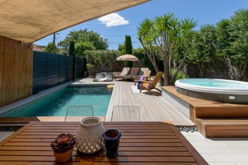 a backyard with a swimming pool and a patio with chairs and a table at Villas les Capucines in Sète