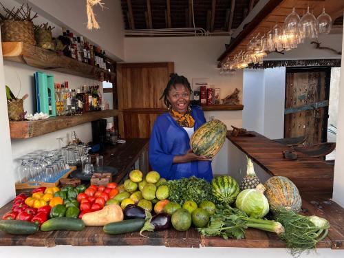 a woman standing in a kitchen with a pile of fruits and vegetables at The View of Zanzibar in Michamvi