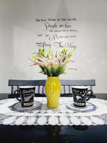 uma mesa com duas chávenas e um vaso com flores em Marco's Lounge 1 em Imus