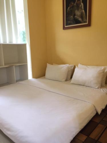 a bed with white sheets and pillows in a room at House at Taman Dayu in Pasuruan