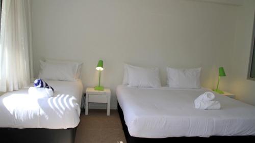 two beds in a room with white sheets and towels at Darwin Waterfront Short Stay Apartments in Darwin