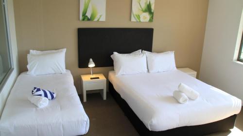 two beds in a room with white sheets and pillows at Darwin Waterfront Short Stay Apartments in Darwin