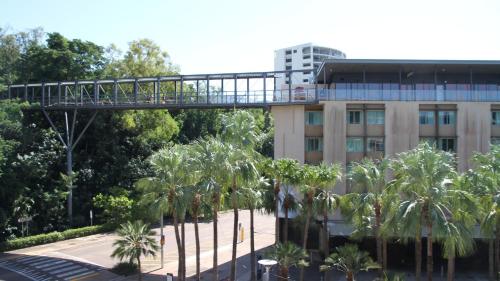 a pedestrian bridge over a street in front of a building at Darwin Waterfront Short Stay Apartments in Darwin