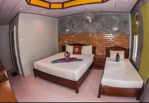 a bedroom with two beds and a brick wall at Lanta New Beach Bungalows - SHA Plus in Ko Lanta