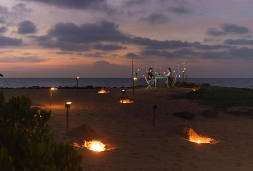 two people sitting at a table on the beach at night at Elements Beach & Nature Resort in Kalpitiya