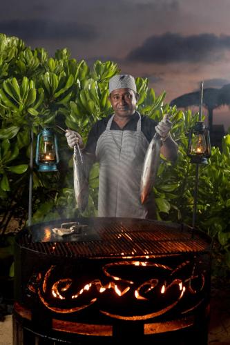 a man holding up some fish on a grill at Elements Beach & Nature Resort in Kalpitiya