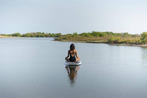 a woman sitting on a surfboard in the water at Elements Beach & Nature Resort in Kalpitiya
