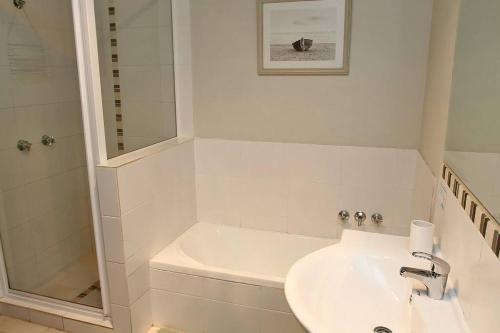 a white bathroom with a sink and a shower at KIAMA AMITY POINT in Amity Point