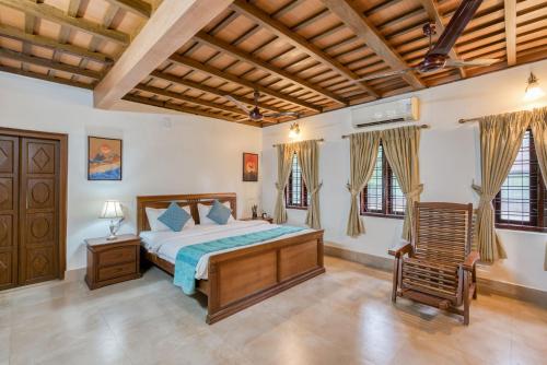 a bedroom with a bed and a chair in it at The Backwater Heritage -Unwind on tranquil Alleppey backwaters in Alleppey