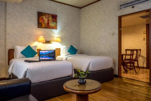 a hotel room with two beds and a laptop on a table at The Hills Batam in Nagoya