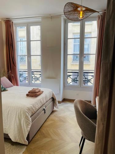 une chambre avec un lit, une chaise et des fenêtres dans l'établissement Le Nid Douillet de Patricia, à Paris