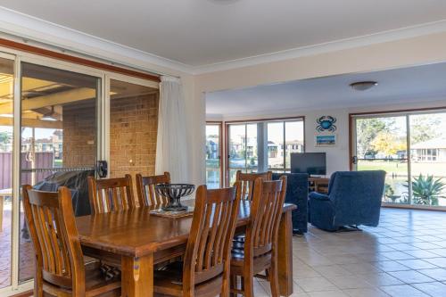 a dining room with a wooden table and chairs at Fishermans Delight Waterfront in Sussex inlet