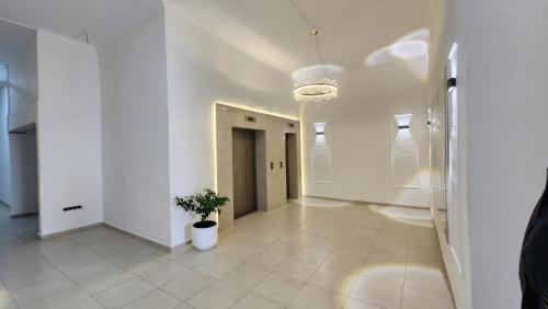 a white hallway with a potted plant in it at Watching The Sea Apartment in Batumi