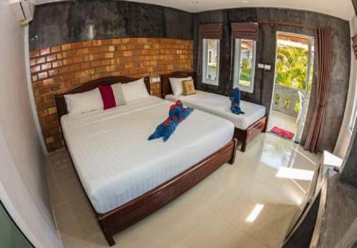 a bedroom with two beds and a brick wall at Lanta New Beach Bungalows - SHA Plus in Ko Lanta