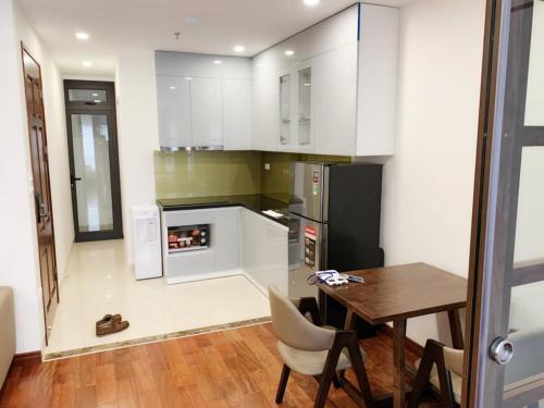 a kitchen with white cabinets and a wooden table and a dining room at HANA Stay in Hanoi