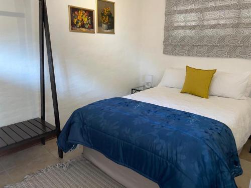 a bedroom with a bed with a blue blanket on it at Comfrey cottage in Kloof