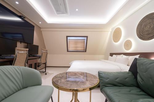 a hotel room with a bed and a table and chairs at From H About Hotel Chunju in Chungju