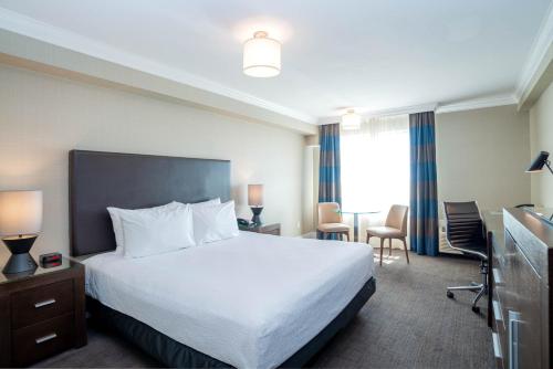 a hotel room with a bed and a table and chairs at Sandman Hotel Oakville in Oakville