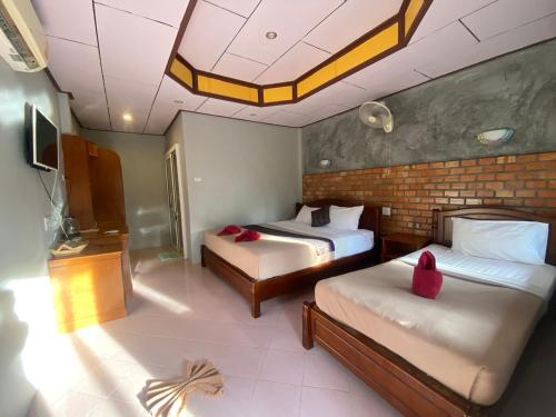 a bedroom with two beds and a brick wall at Lanta New Beach Bungalows - SHA Plus in Ko Lanta
