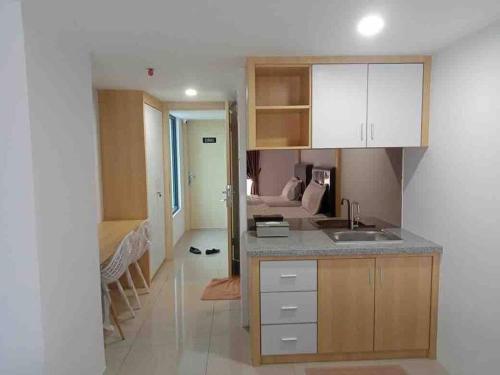 a kitchen with a sink and a room with a bed at Studio unit Deprima Apartemen in Medan