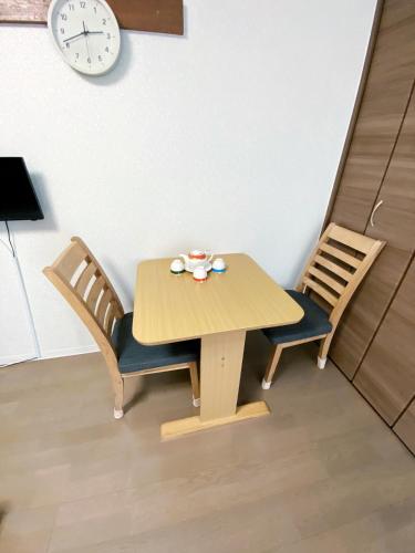 a wooden table with two chairs and a clock on the wall at A&B Omoromachi Station in Naha