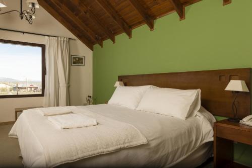 a bedroom with a bed with white sheets and a window at Hosteria Roblesur in El Calafate