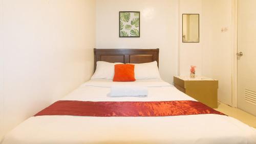a bedroom with a bed with an orange pillow at Nearest Hostel Pasay City by RedDoorz in Manila