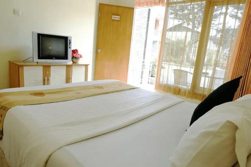 a bedroom with a bed and a tv and a window at Hotel Pesona Ciwidey in Ciwidey