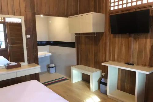 a room with a bed and a tv and a desk at Hotel Pesona Ciwidey in Ciwidey