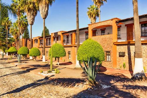 une rangée de palmiers devant un bâtiment dans l'établissement Hotel Real de Minas Tradicional, à Querétaro