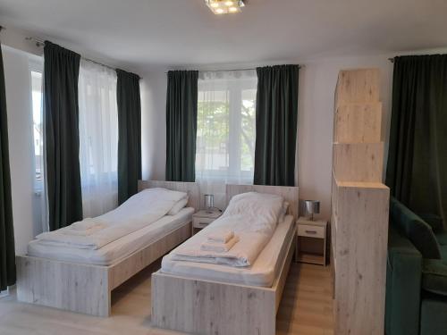 2 camas individuales en una habitación con ventanas en Orion Panzió, en Hajdúszoboszló