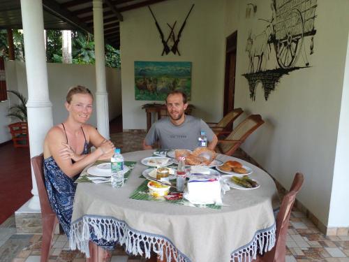 Ein Mann und eine Frau sitzen an einem Tisch mit Essen in der Unterkunft New Toropi Homestay in Gadaladeniya