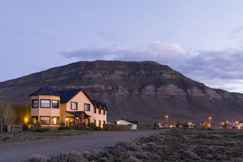 a house on the side of a road in front of a mountain at Hosteria Roblesur in El Calafate