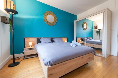 Dormitorio azul con cama y espejo en KASA Cocon - Entièrement équipé avec Balcon, en Saint-Étienne