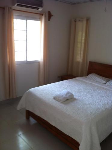 a bedroom with a white bed with a window at Casa Loma in Pedasí Town