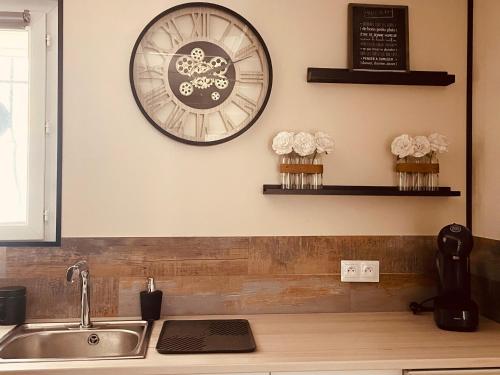 une cuisine avec un évier et une horloge murale dans l'établissement Chez So', à Martigues