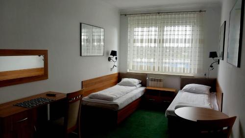 Habitación con 2 camas, escritorio y mesa. en Hotel i Restauracja 13 Smaków, en Częstochowa