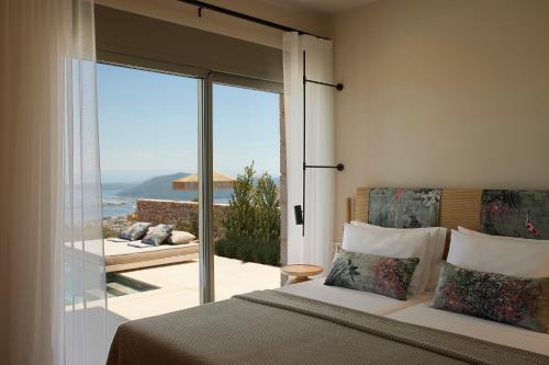 a bedroom with a bed and a view of the ocean at Epiphany Villas Lefkada in Tsoukaladhes