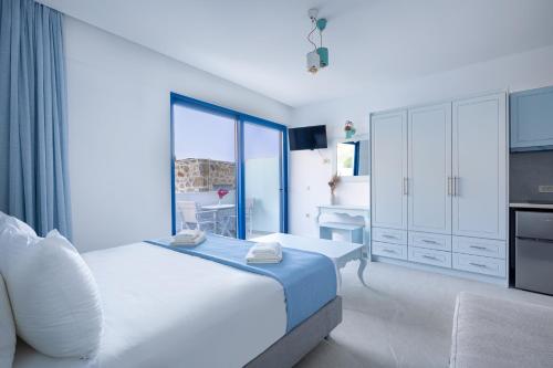 a white bedroom with a bed and a television at Molos Apartments in Loutro