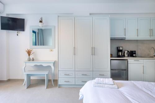 a kitchen with white cabinets and a table in a room at Molos Apartments in Loutro
